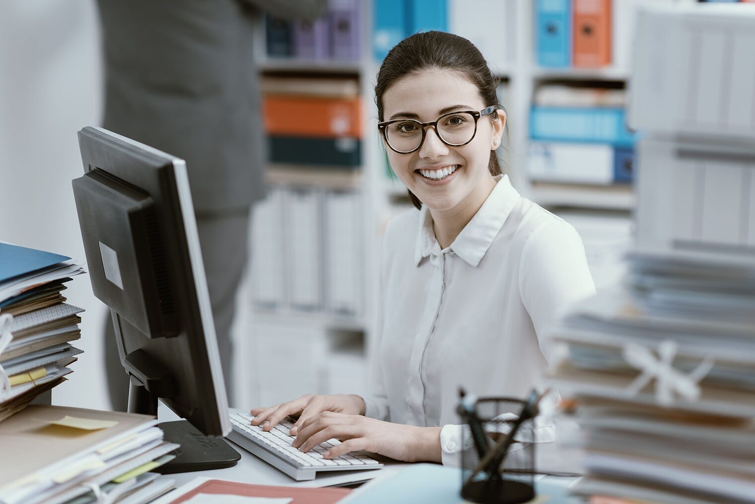 Junge Frau sitzt im Büro an ihrem Schreibtisch
